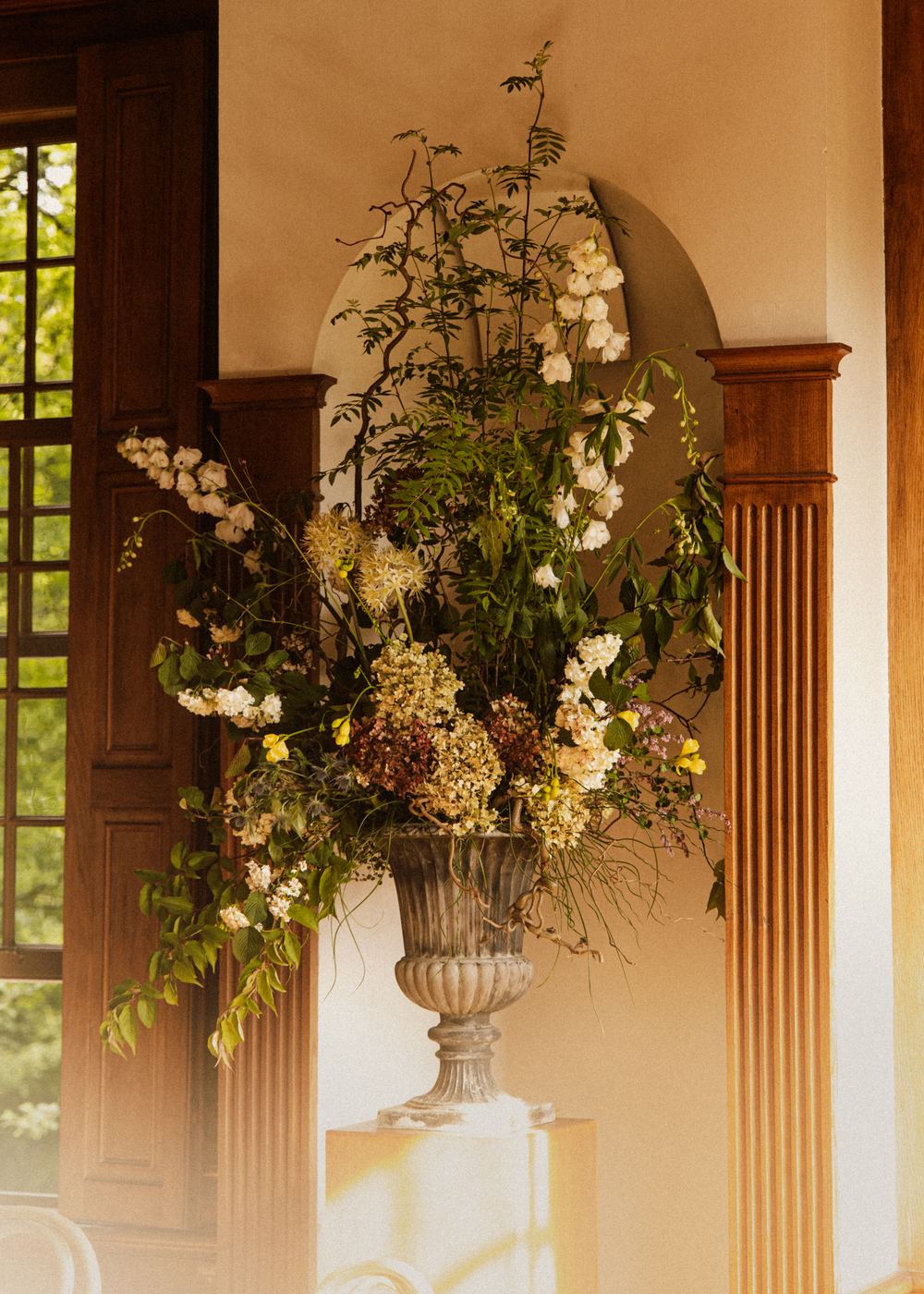 Urn met bloemen in een nis tussen houten pilasters