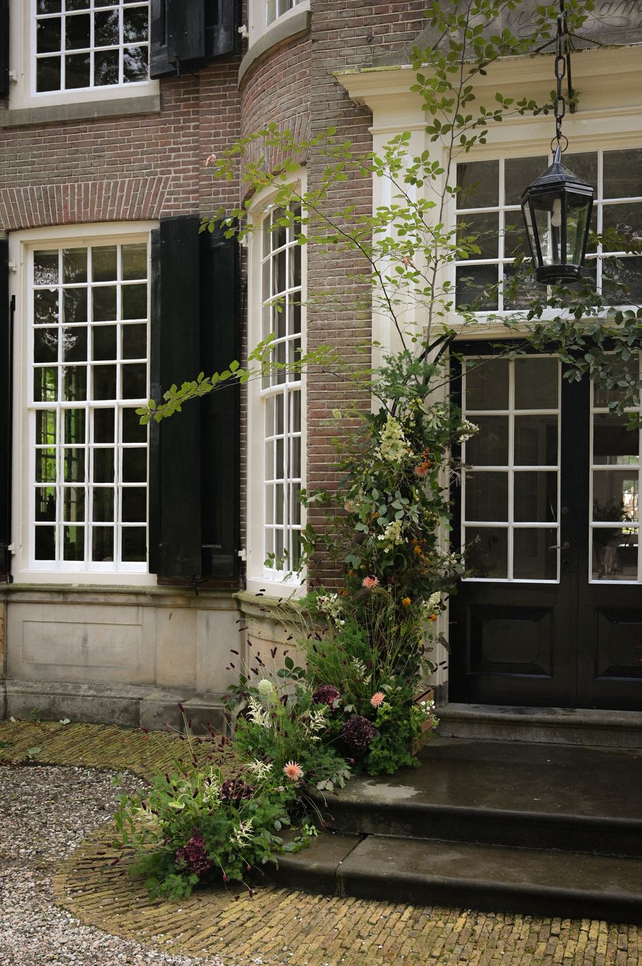 Bloeminstallatie langs de voordeur met lantaarn